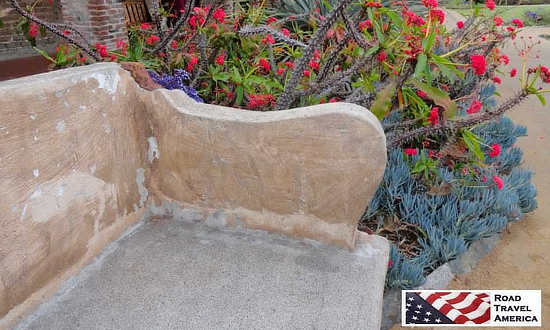 Lovely stone bench and blooming cactus at the Mission of San Juan Capistrano in California