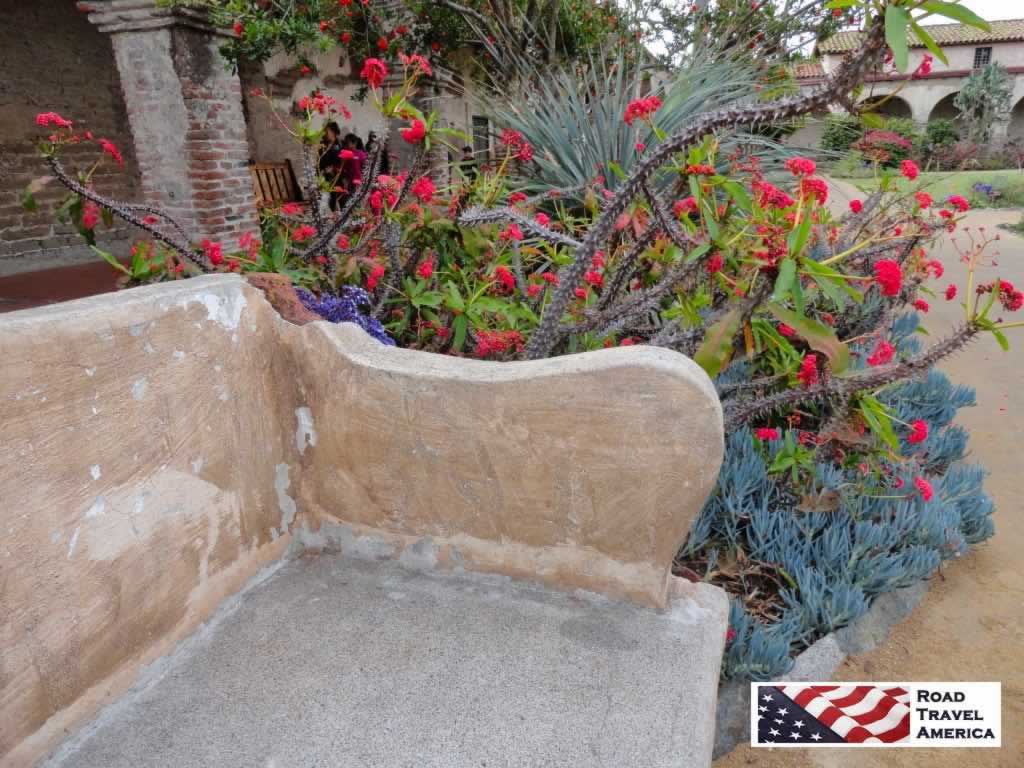 Lovely stone bench and blooming cactus at the Mission of San Juan Capistrano in California