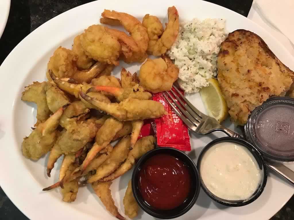 Fried seafood spectacle in Destin: Crab claws, shrimp and fish with twice-baked potatoe and cole slaw