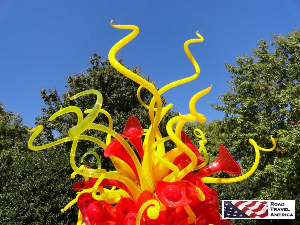 Bright yellow and red Chihuly art glass against the brilliant blue Dallas sky at the Arboretum