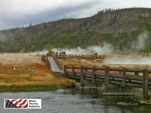 Visitors walk a wooden bridge across a geothermal area at Yellowstone National Park